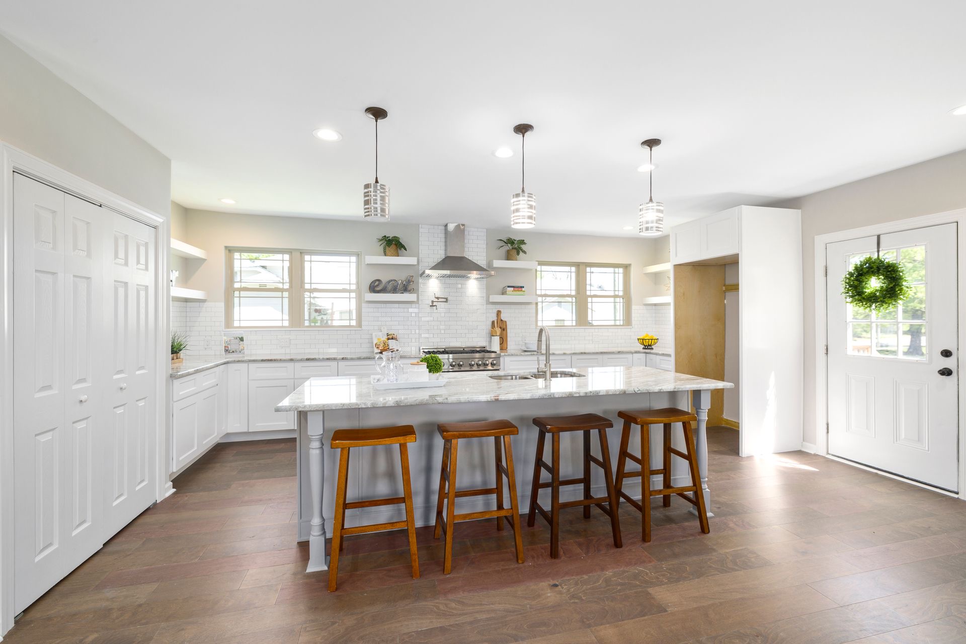 Bright finished kitchen with a large island, wood stools, and morning light through multiple windows