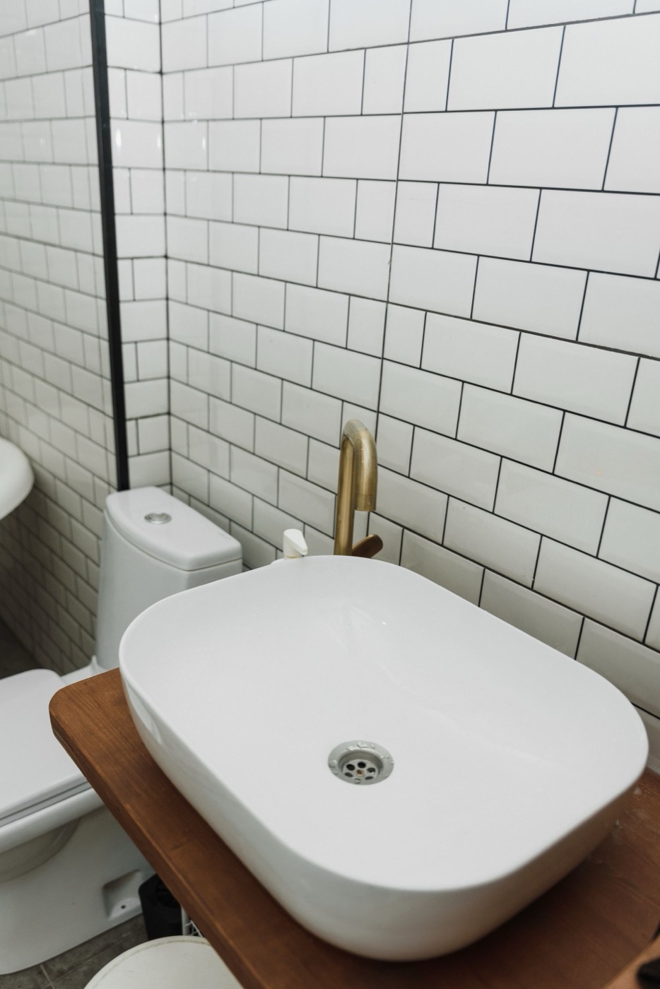 Brass faucet and vessel sink detail against white subway tile in a finished bathroom
